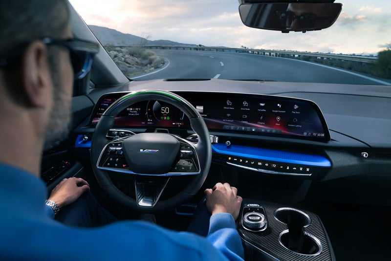 Front View of the 2026 OPTIQ-V Driving Through the Dusk Utilizing its Headlights | Cadillac of Norwood in Norwood MA