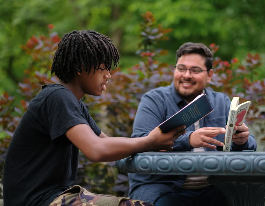 Mentor reading with youth outdoors