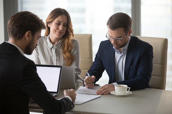 Three people signing paperwork for Sell It Now at a conference table in Norwood, MA